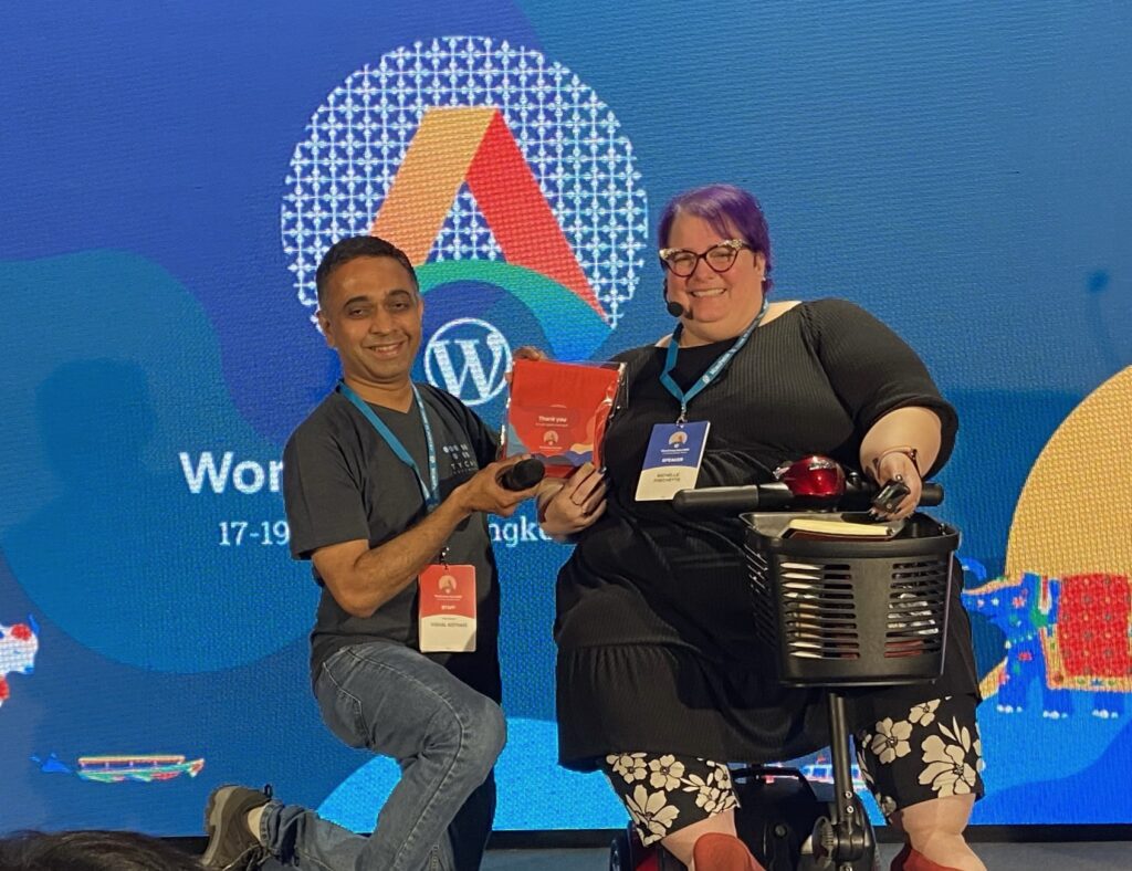 Michelle receiving a speaker gift on stage at WordCamp Asia 2023.