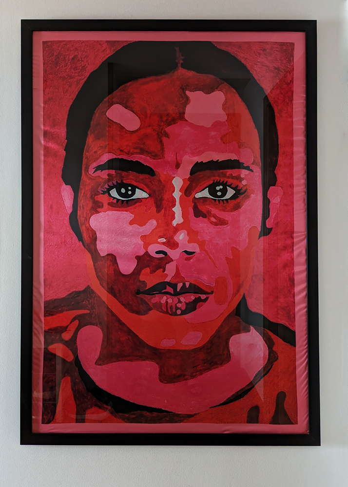A painting in shades of red and pink of a person looking toward the viewer.
