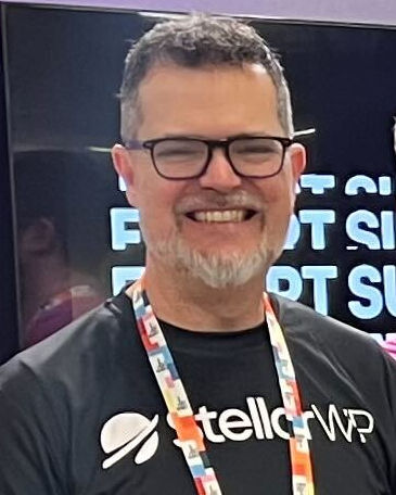 Person wearing a black 'StellarWP' t-shirt and glasses, smiling at an event.